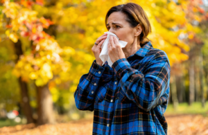 Woman outdoors on a fall afternoon holding a tissue to her nose from ragweed allergies near Vancleave