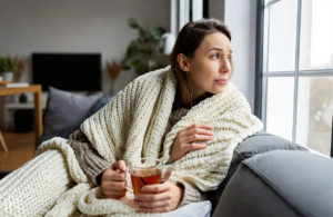 Woman resting at home with tea, feeling under the weather during flu and COVID season on the Gulf Coast