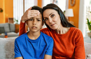 A Pascagoula-area mother checks her son for a fever at home before a same-day clinic visit