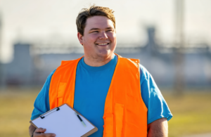 A new hire in a hi-vis vest holding paperwork before a pre-employment drug screen near Pascagoula
