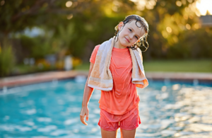 Young girl by a Gulf Coast pool tilting her head to drain water from her ear after swimming