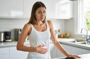 Woman holding her lower abdomen with UTI discomfort at home in Vancleave
