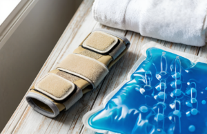 Wrist brace and blue gel ice pack on a wooden table for a broken wrist or sprained wrist