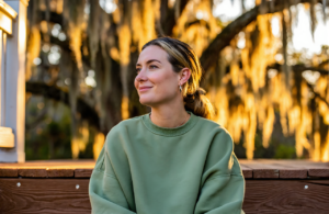 Young woman in a green sweatshirt on a Gulf Coast back porch, calmly considering STD testing near Biloxi, MS