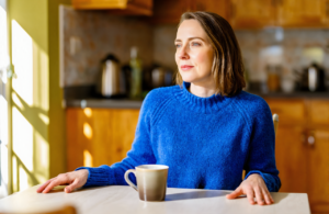 Woman at a sunlit kitchen table weighing urgent care cost without insurance in Vancleave MS