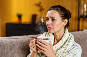 Woman with a cold resting at home with tea, urgent care near Ocean Springs MS